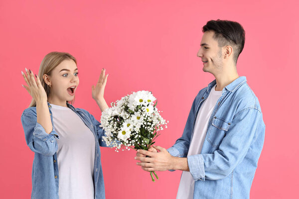 A guy gives a bouquet to a girl on pink background