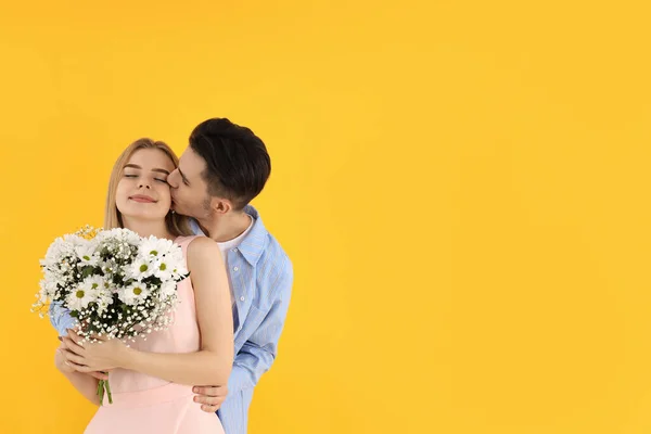 带黄色背景花束的年轻夫妇 — 图库照片