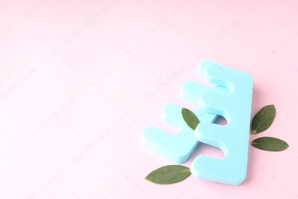 Nail separators and leaves on pink background