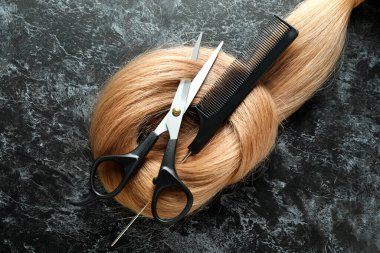 Makasla kadın saçı ve arka planda saç fırçası.