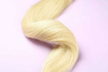 Mor arka planda bir tutam sarı kadın saçı.