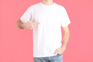 Pembe arka planda beyaz tişörtlü bir adam.