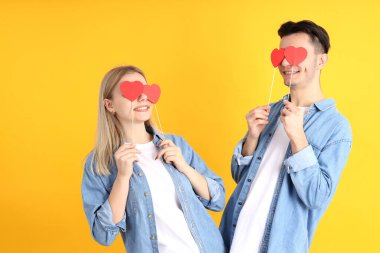 Sarı arka planda kalpleri olan sevimli bir çift.