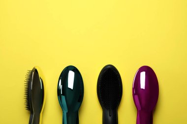Sarı arkaplanda renkli plastik saç fırçaları
