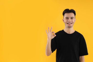 Sarı arka planda tişörtlü çekici bir genç.