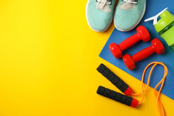Fitness accessories on yellow background, top view