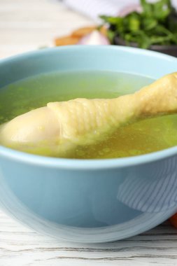 Beyaz ahşap arka planda tavuk çorbası, yakın plan.