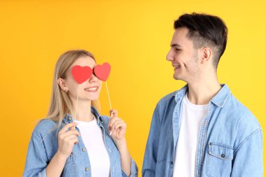 Sarı arka planda kalpleri olan sevimli bir çift.