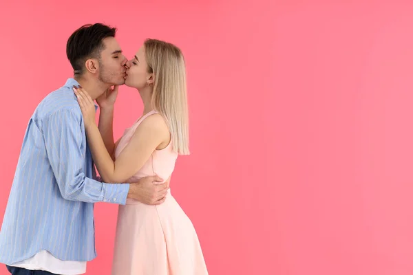 可爱而快乐的情侣在粉色背景下接吻 — 图库照片