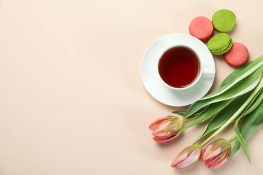 Çay, lale ve bej arka planda badem kurabiyesi.