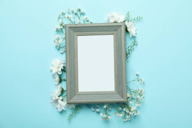 Mavi arkaplanda çiçekli boş fotoğraf çerçevesi