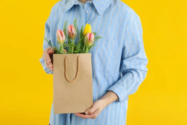 Vrouw Houdt Papieren Zak Met Bloemen Gele Achtergrond — Stockfoto