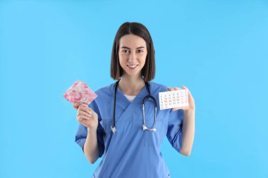 Female nurse with period calendar and pads on blue background
