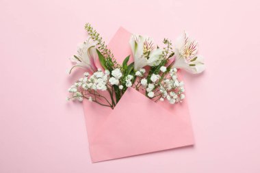 Blank envelope with flowers on pink background