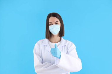 Female doctor in mask and gloves on blue background