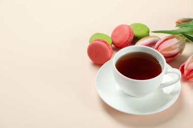 Çay, lale ve bej arka planda badem kurabiyesi.