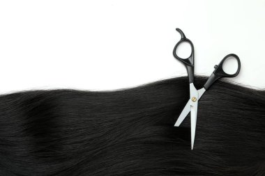 Female hair and scissors on white background