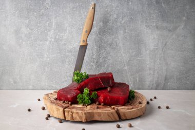 Concept of cooking with raw beef steaks against gray textured background