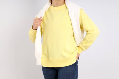 Açık gri arka planda, boş kazaklı bir kadın.