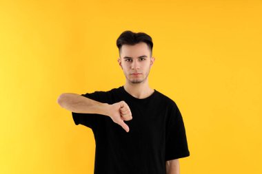 Sarı arka planda tişörtlü çekici bir genç.