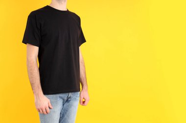 Sarı arka planda siyah tişörtlü adam.
