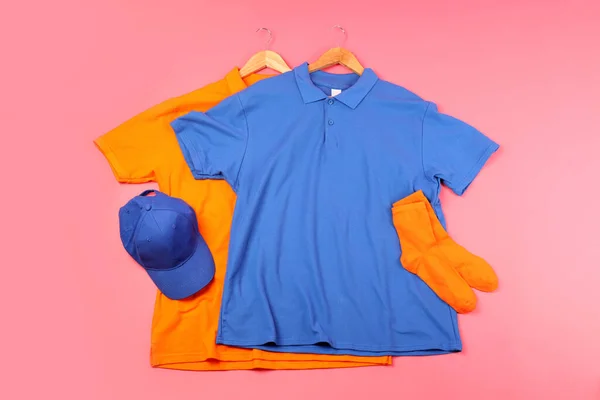 Blank t-shirts, socks and cap on pink background