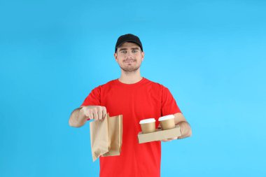 Mavi arka planda yemek getiren teslimatçı.