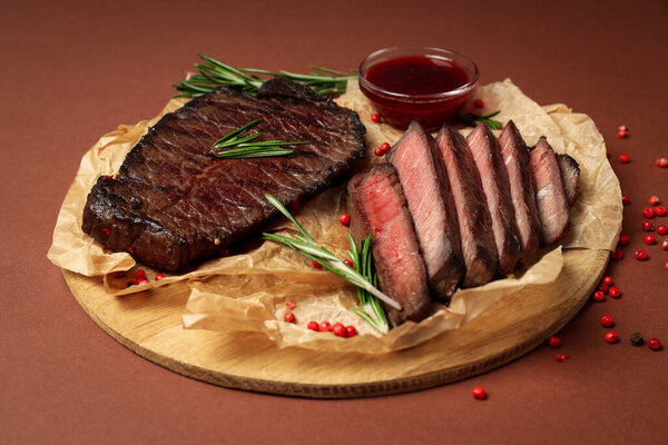 Concept of tasty food with beef steaks on brown background