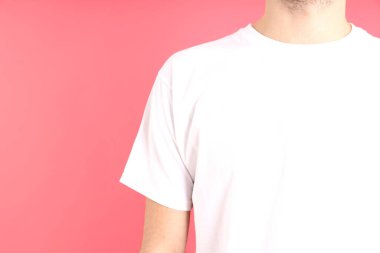 Pembe arka planda beyaz tişörtlü bir adam.