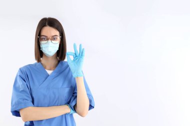 Kadın stajyer hemşire eldivenli ve maske takıyor.