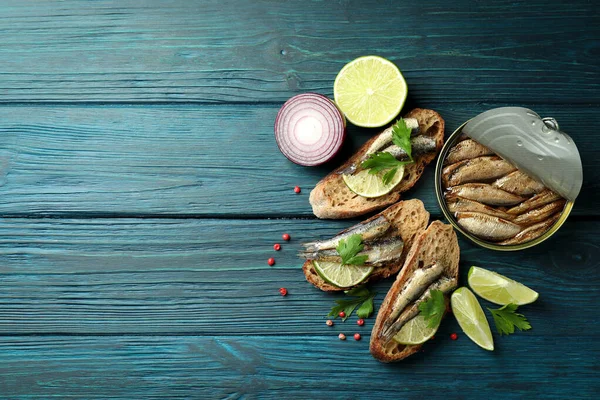 Concept of tasty snack with sandwiches with sprats on wooden background