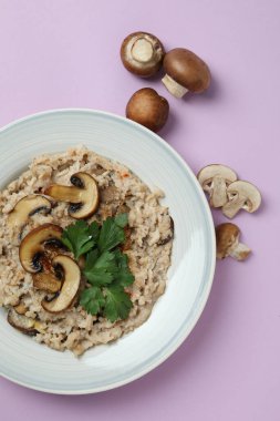 Mantarlı risotto tabağı ve mor arka planda malzemeler