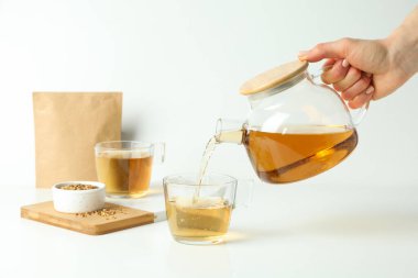 Kadın eli cam bardağa karabuğday çayı döker.