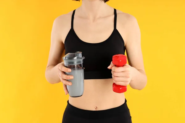 Sportovní Žena Drží Proteinový Koktejl Činka Žlutém Pozadí — Stock fotografie