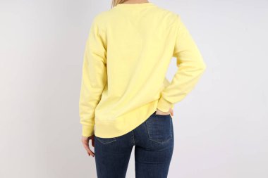 Açık gri arka planda, boş kazaklı bir kadın.