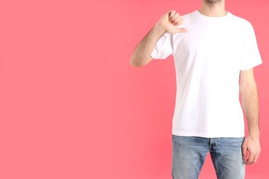 Pembe arka planda beyaz tişörtlü bir adam.