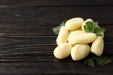 Ahşap arka planda maydanozlu çiğ patates gnocchi.