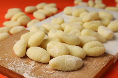Turuncu arka planda çiğ patates gnocchi ile kesme tahtası