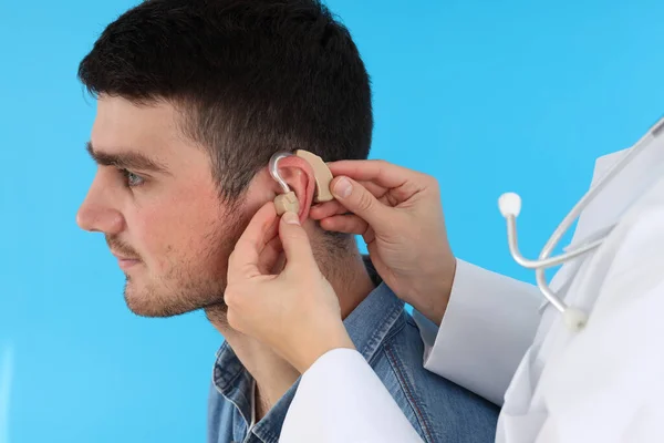 Médico Instala Audífonos Oído Del Joven Sobre Fondo Azul —  Fotos de Stock