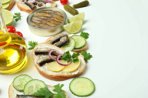 Concept of tasty snack with sandwiches with sprats on white background