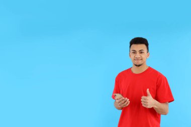 Mavi arka planda telefonu olan genç bir adam.