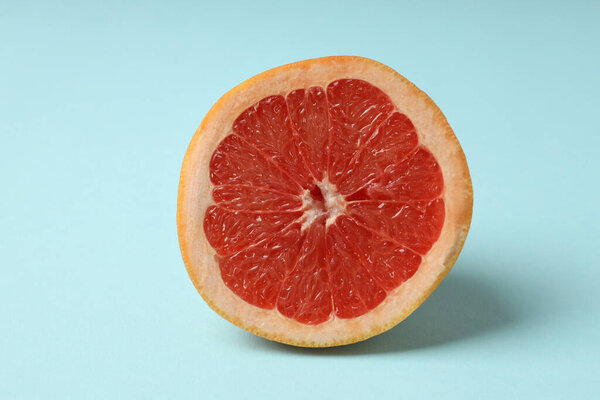 Half of grapefruit on blue background, close up