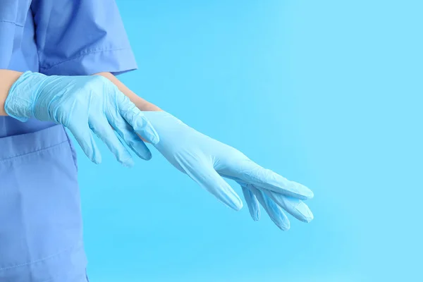 女医生戴上蓝色背景手套 — 图库照片