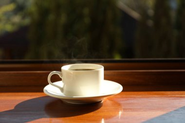 Bir fincan çay ahşap pencere eşiğinde duruyor.