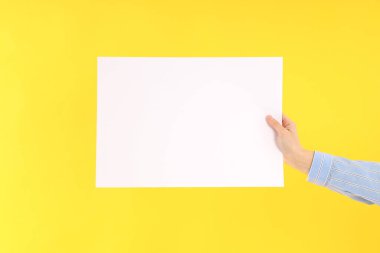 Sarı arka planda boş afiş tutan kadın.