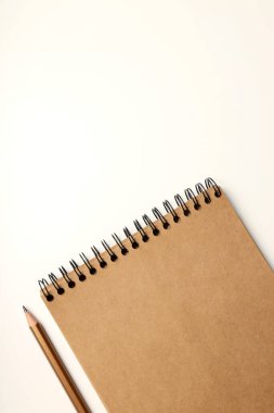 Beyaz arkaplanda kurşun kalem bulunan bir defter