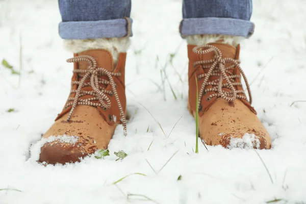 Woman in boots stands on snow, close up