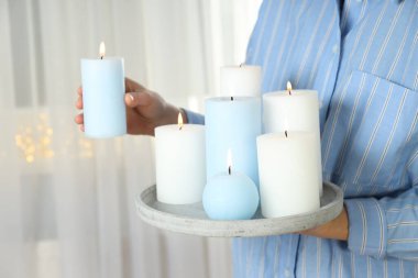 Kadın tepsiyi mavi ve beyaz aroma mumlarıyla tutuyor.