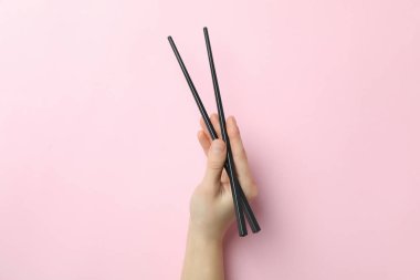 Pembe arka planda kadın yemek çubukları