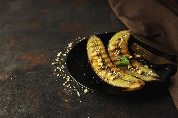 Concept of tasty food with grilled banana on dark textured background